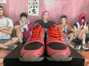 Front view of black and pink Nike basketball sneakers showing orange laces, black perforated toe areas, and basketball-player logos on the tongues.