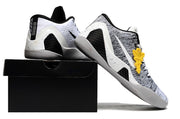 White and black shoes displayed on a black shoebox.