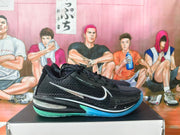 Side view of a black basketball shoe with a silver swoosh and blue and mint outsole.
