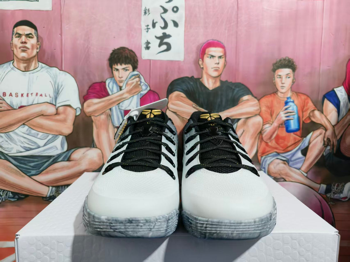 Front view of white and black GiGi basketball sneakers with gold tongue details, displayed on a white box.