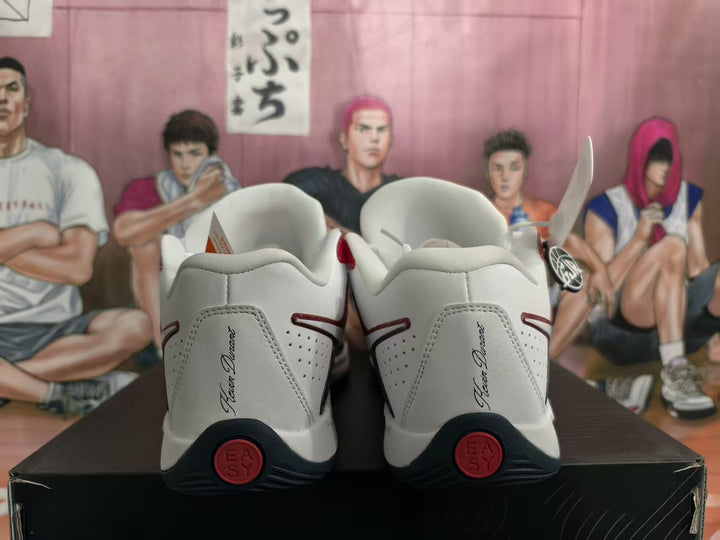 Rear view of white Nike basketball sneakers with red and black heel details, displayed on a black shoebox.