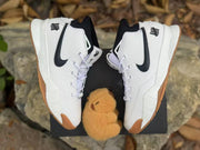 Top view of a pair of white high-top sneakers with black Swoosh branding and gum-colored outsoles.