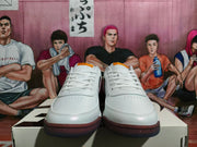 Front view of a pair of white low-top lace-up sneakers with burgundy and dark outsole edges.