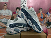 Pair of white and navy Nike sneakers displayed at an angle, highlighting the patterned side panels, swooshes, and rounded cushioning details.