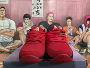 Front view of red basketball-style sneakers with red laces, black accents, and gold-toned tongue logos.