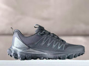 Side view of a black Alo all-terrain hiking sneaker showing the layered upper, structured laces, heel pull tab, and lugged outsole.