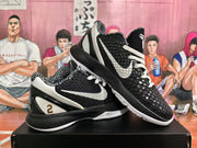 Angled view of a pair of black and white basketball sneakers displaying the textured uppers, white swooshes, contrasting midsoles, and heel details.