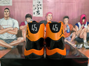 Rear view of black and orange high-top basketball sneakers with Jordan branding and size 45 visible on the tongue labels.