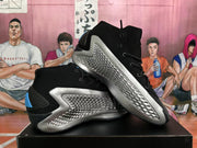 Pair of black and silver Adidas basketball sneakers displayed at an angle, highlighting the textured silver side panels.