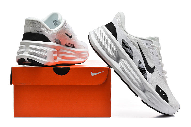 White and black Nike running sneakers displayed with an orange shoe box