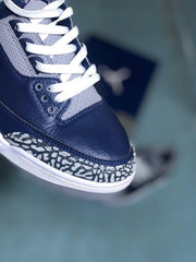 Close-up of the navy toe, grey lace panels, white laces, and elephant-print overlay.