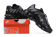 Black and grey Nike Air Max Plus sneakers displayed on a red shoe box; the box label shows sample sizes EU 40 and EU 42.