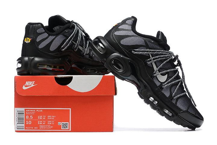 Black and grey Nike Air Max Plus sneakers displayed on a red shoe box; the box label shows sample sizes EU 40 and EU 42.