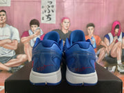 Rear view of a pair of blue Nike Kobe basketball shoes with red signature details on the heels.