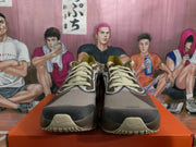 Front view of Nike running shoes showing cream laces, layered brown and gray panels, and textured toe areas.