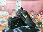 Side view of black Nike basketball sneakers showing the gold Swoosh and textured patterned outsole.