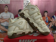 Angled side view of beige Nike Air More Uptempo sneakers with brown outsole accents