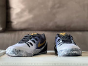 Front view of the pair with black laces, white toe boxes, dark collars, and gold tongue details.