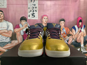 Front view of gold basketball shoes with burgundy laces and dark tongue logos