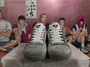 Front view of the sneakers showing white laces, woven gray-and-black uppers, black accents, and gray outsoles.