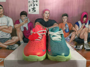 Front view of red and teal Nike sneakers with perforated toes, contrasting laces and translucent green outsoles.