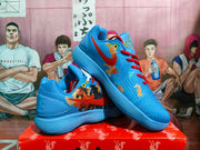Pair of blue Nike basketball sneakers with red laces, graphic side detailing, and a layered blue outsole displayed on a box.