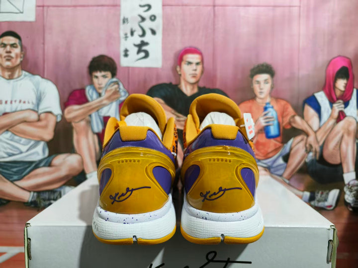 Rear view of yellow and purple Nike basketball shoes showing padded collars, white speckled midsoles, and yellow outsoles.