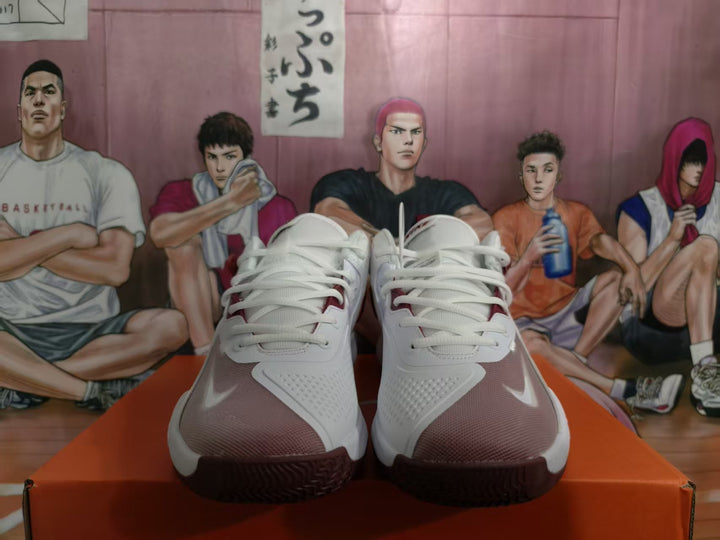 Front view of white and dark red Nike basketball sneakers displayed on an orange shoebox.