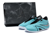 Turquoise Nike sneakers pictured beside a dark shoe box.