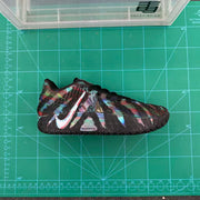 Side profile of a multicolor Nike sneaker placed on a green cutting mat, with the Swoosh and ZoomX marking visible.