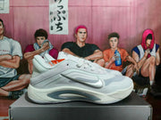 Side profile of a white Nike basketball sneaker with a silver-gray Swoosh, layered upper, and sculpted midsole.