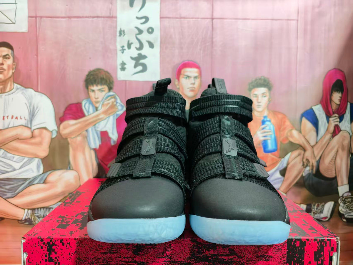 Front view of black Nike high-top basketball shoes with multiple straps and light blue outsoles.