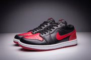 Pair of black and red low-top sneakers shown at an angled front view with perforated toe panels.