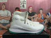 Side view of a white high-top basketball shoe with a teal outsole