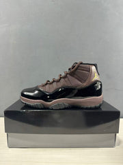 Side profile of a black and bronze Air Jordan 11 Retro high-top sneaker.