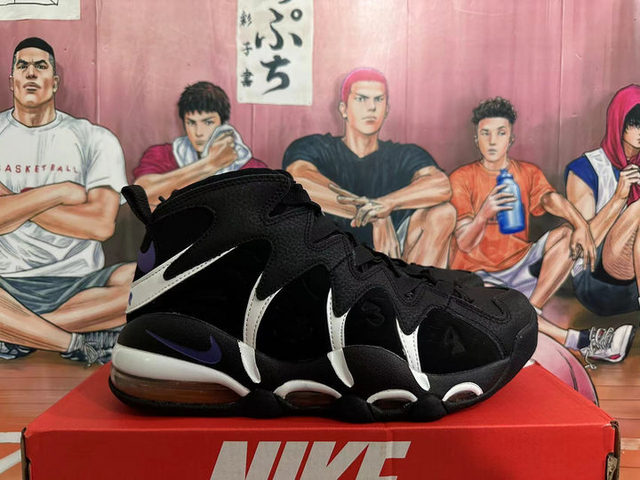 Black high-top Nike basketball shoes with white overlays and purple accents, shown from the side.