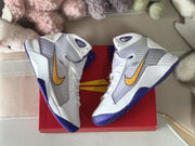 Top-down view of the white and purple sneaker pair placed on a red box.