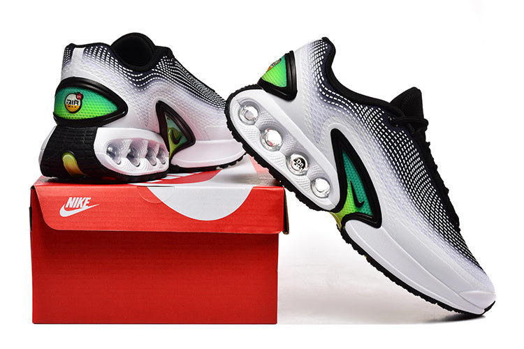Pair of white, black, and green Nike Air Max sneakers displayed with a red shoebox.