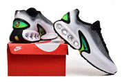 Pair of white, black, and green Nike Air Max sneakers displayed with a red shoebox.