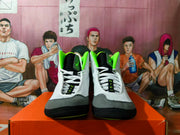 Front view of gray and black Nike wrestling shoes with bright green accents and white laces.