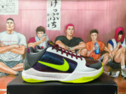 Side view of a Nike basketball shoe with white and dark purple panels, a yellow-green Swoosh, and a speckled white midsole.
