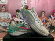 Pair of beige Nike basketball sneakers shown at an angle, with teal and purple accents, pink Swoosh details, and a speckled midsole.