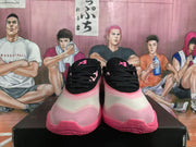Front view of black and pink basketball sneakers displayed on a black shoe box.