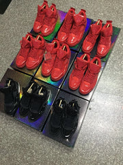 Display of multiple red and black high-top footwear styles arranged on colorful platforms; not a close-up of the featured pair.