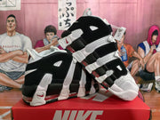 Angled view of the pair showing the high-top shape, layered side construction, white outsole sections, and red accent details.