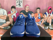Front view of blue basketball shoes with textured uppers, dark blue laces, white Swoosh-style logos, and Kobe-style tongue branding.