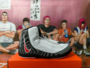 Side view of a gray and black Nike wrestling-style shoe with a red-and-white side swoosh on an orange shoebox.