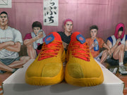 Front view of orange Curry basketball shoes with red-orange laces, blue tongue details and textured toe panels.