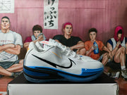 Side view of a white Nike GT basketball shoe with a black side logo and blue outsole accents