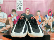 Front view of black Adidas sneakers with white side overlays and red tongue marks